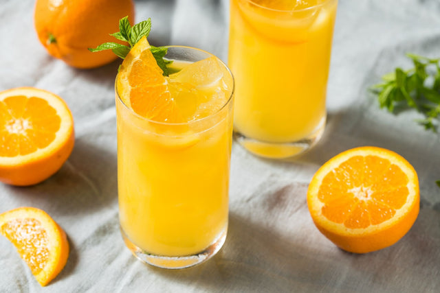 Flora Screwdriver THC cocktail in two glasses of fresh orange juice over ice, garnished with mint and orange slices